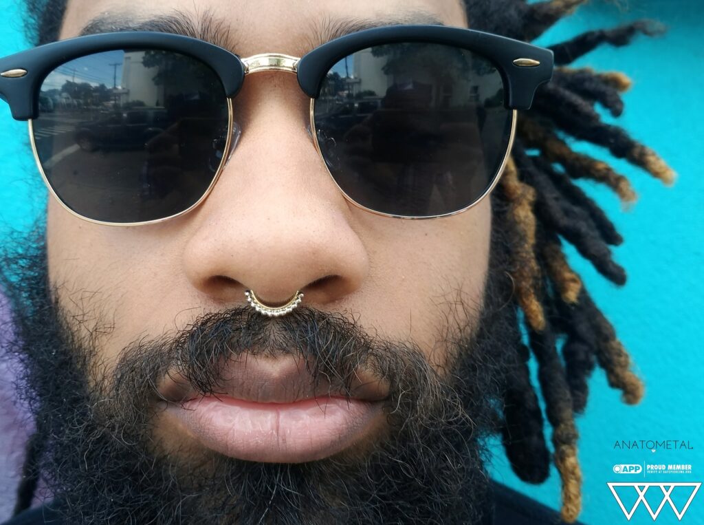 A healed septum piercing adorned with an 18k yellow and white gold 'Vaughn' seam ring from Anatometal, showcasing a luxurious two-tone design that enhances the symmetry and elegance of the nose.