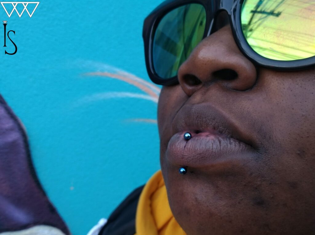 A vertical labret piercing featuring an anodized titanium curved barbell from Industrial Strength, showcasing a vibrant "blurple" hue that adds a personalized touch to the lower lip.