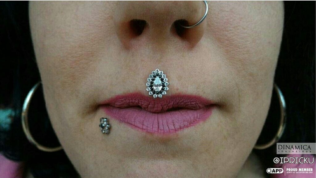 Close-up of a healed philtrum (medusa) piercing featuring an 18k white gold “Laura” threadless end from Dinamica Joalheiros, adorned with alternating black and white Swarovski gemstones.