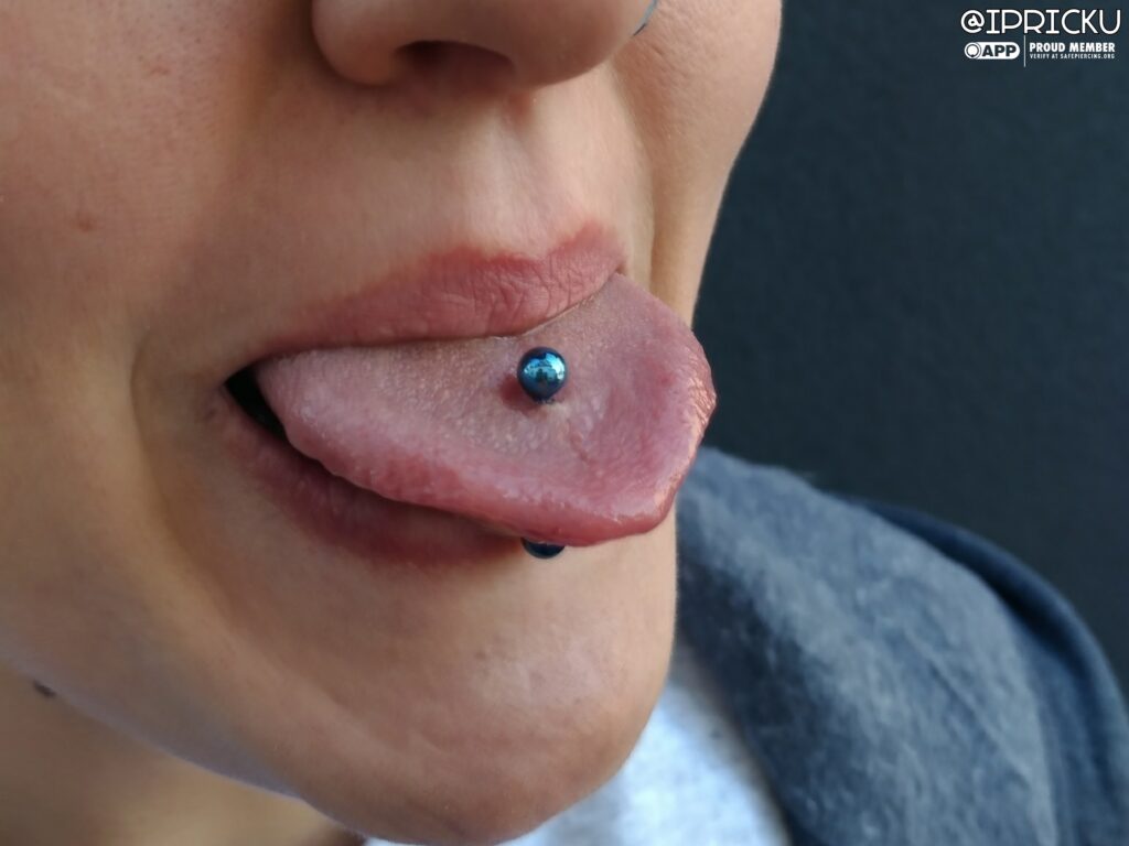 Fresh tongue piercing featuring an anodized titanium straight barbell from Industrial Strength, highlighting the sleek finish and precise placement.