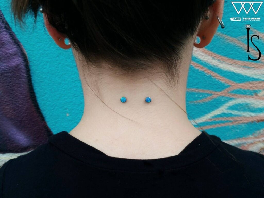 Long-healed surface piercing featuring upgraded bezel-set blue opal ends from Industrial Strength, showcasing vibrant color and excellent placement.