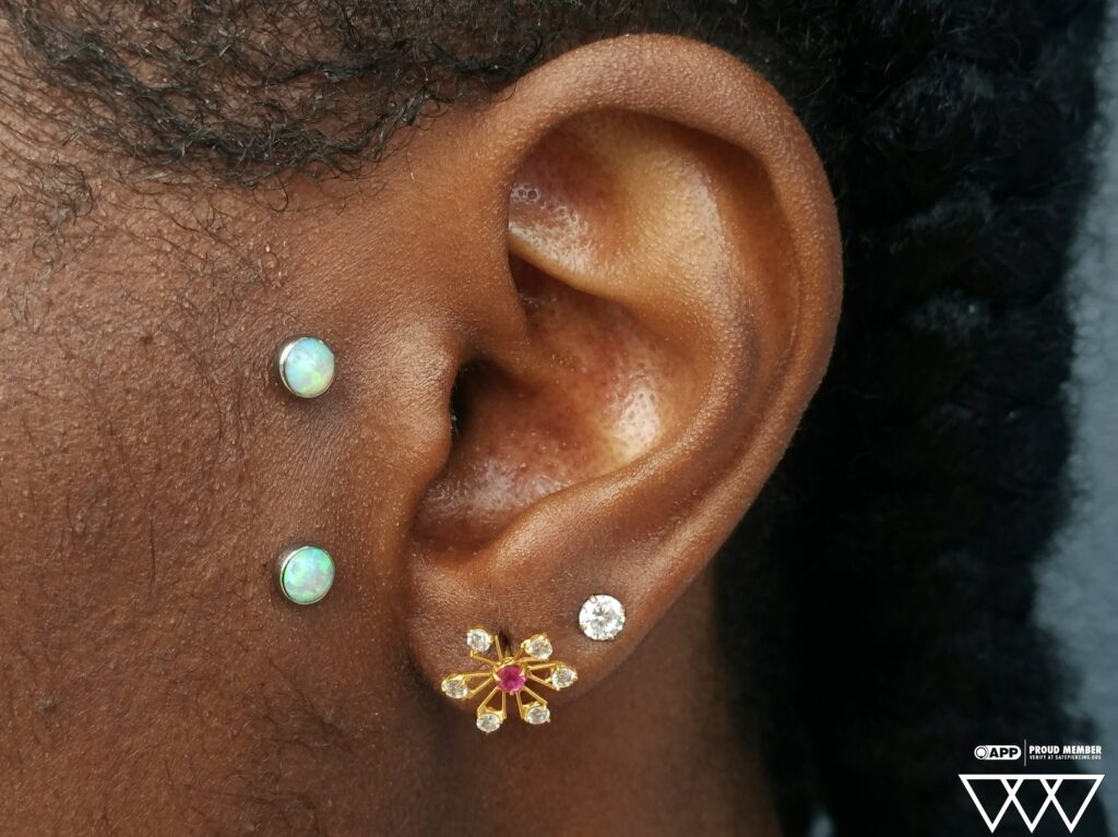 The Bronx Alternative – Safe, Expert Piercing Without the Shop Drama Close-up of a healed surface piercing featuring a titanium staple bar from Industrial Strength, adorned with bezel-set white opal tops. The jewelry lies flush against the skin, showcasing the opals' iridescent shimmer and the precision of the piercing placement.