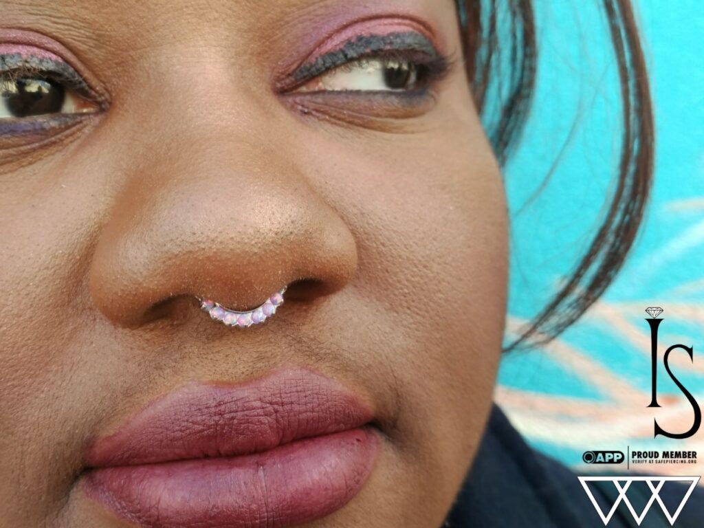 Piercing Studio for Perth Amboy. Private, Expert Care A healed septum piercing adorned with a titanium 'Odyssey' clicker from Industrial Strength, featuring pink opals that add a sleek and polished touch.