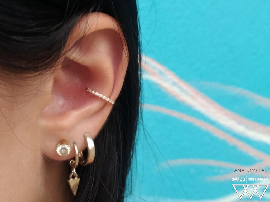 Private Body Piercing Near Menlo Park. Expert, Clean, One-on-One Service A well-healed conch piercing adorned with an 18k gold seam ring from Anatometal, set with 13 sparkling Swarovski gemstones, showcasing a luxurious and timeless design.