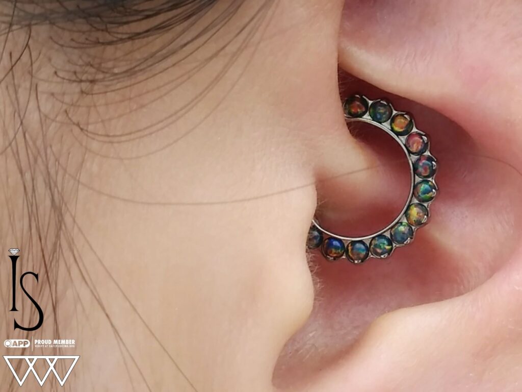 Private Body Piercing Near Edison. Expert Care, High-End Jewelry A fully healed daith piercing adorned with a titanium 'Odyssey' clicker from Industrial Strength, featuring fiery black opals that enhance the inner ear's natural curve.