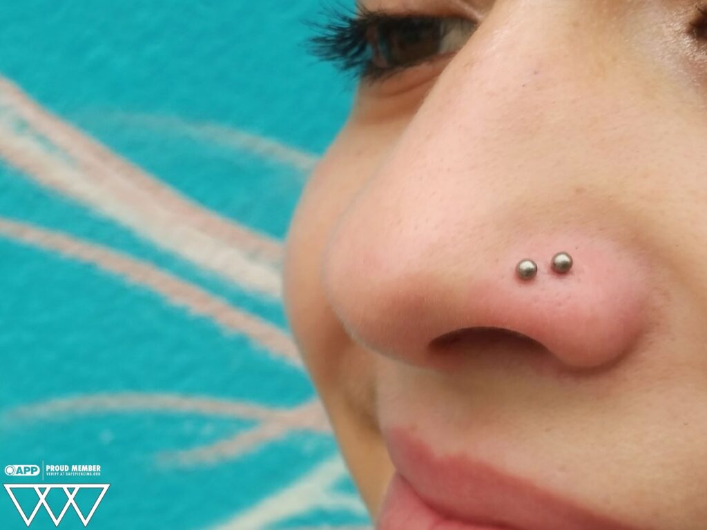 Piercing Studio for Englishtown, Freehold & Old Bridge. Clean, Private Experience A double nostril piercing fitted with classic implant-grade titanium bead ends, positioned symmetrically for a clean, minimalist aesthetic.
