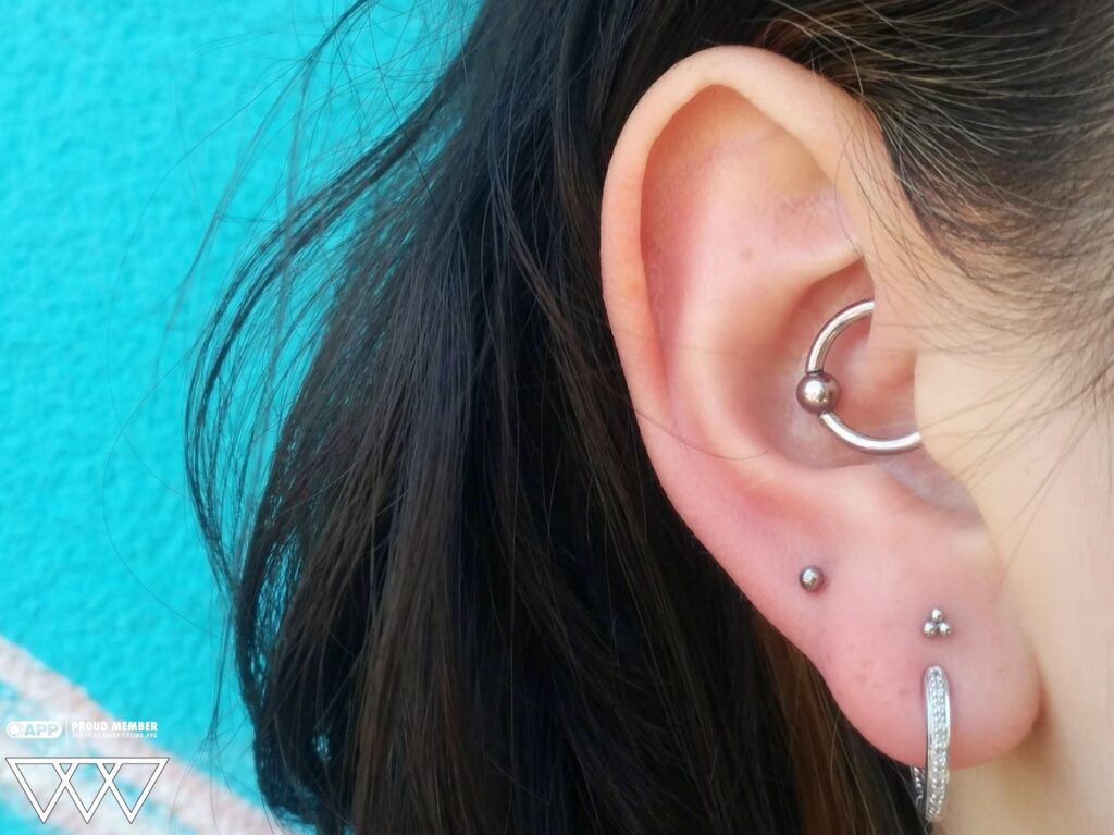 Close-up of a daith piercing featuring a stainless steel captive bead ring from SM316, highlighting the snug fit within the ear's innermost cartilage fold.