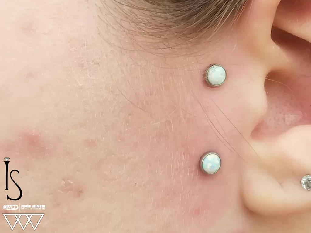 Close-up of a surface piercing adorned with implant-grade titanium jewelry, highlighting the luminous opal settings and expert craftsmanship.